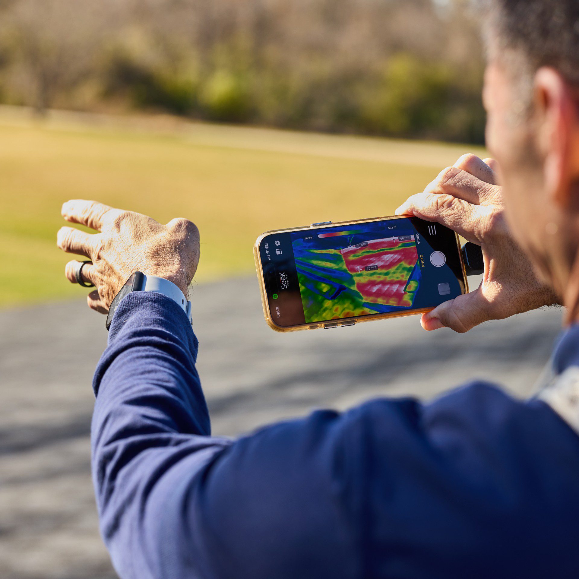 Person playing a mobile game with a VR glove outdoors.